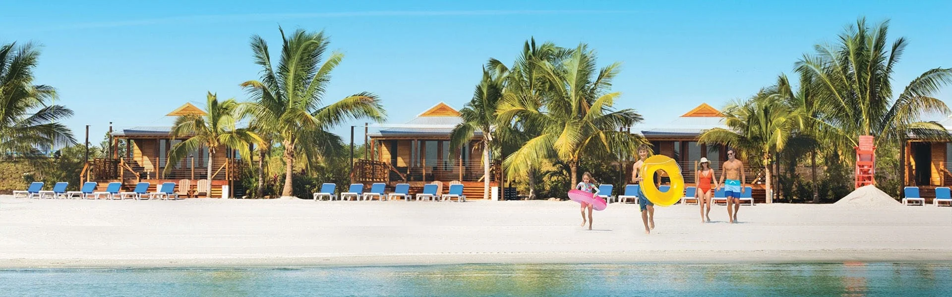Praia de Harvest Caye, Belize, com areia clara, coqueiros e cabanas à beira-mar